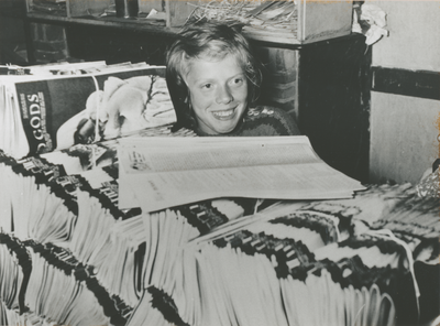 876625 Portret van een meisje achter een grote stapel gebundelde tijdschriften 'De Stad Gods' die door enkele kinderen ...